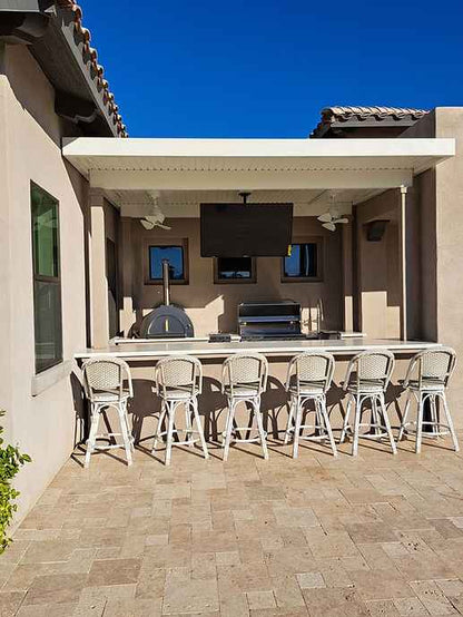 Outdoor patio area with a barbecue grill, chairs, and a television screen.